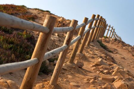 Wooden fence along the rocky dangerous pathの写真素材