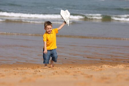 Cute 3-years old boy running with plane made from newspaperの写真素材