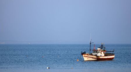 Small fishing boat in blue ocean watersの写真素材