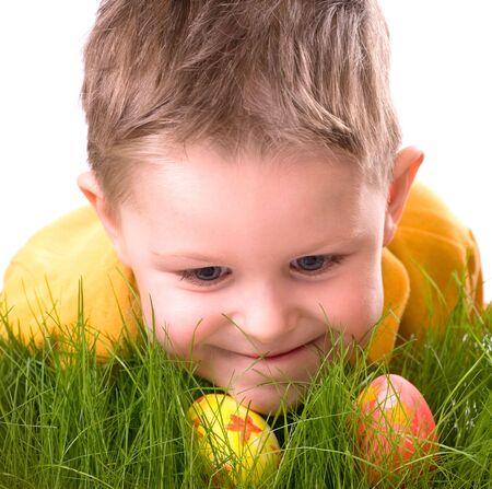 Easter egg hunt. Cute boy searching for easter eggs hidden in fresh green grass. Isolated on white...