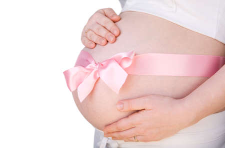 It is a girl. Isolated 29-weeks pregnant belly with pink bow over itの写真素材