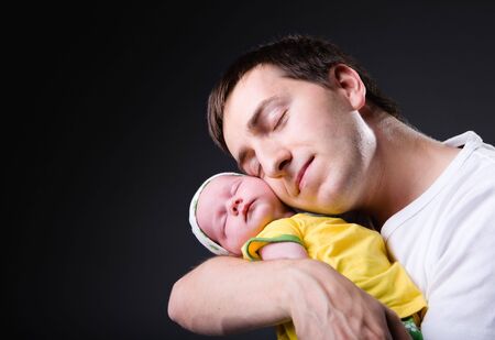 Studio picture of happy young father with his 14 days old newborn daughter over black background