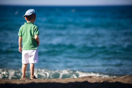 Small boy playing at volcanic black sand beachの写真素材
