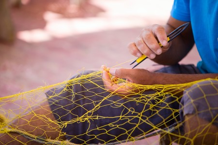 Closeup of fisherman repairing fishing net