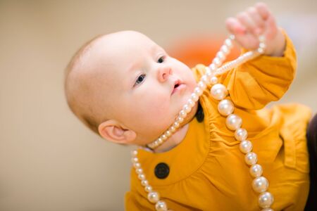 Cute little girl playing with white beadsの写真素材