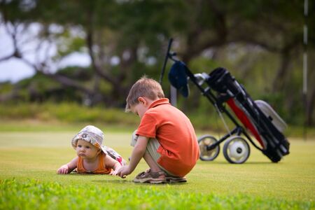 Two adorable kids playing on golf field waiting.の写真素材
