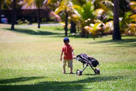 4 years old boy walking with golf bagの写真素材