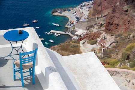 Blue table overlooking pectacular caldera surrounding the beautiful island of Santorini, Greeceの写真素材