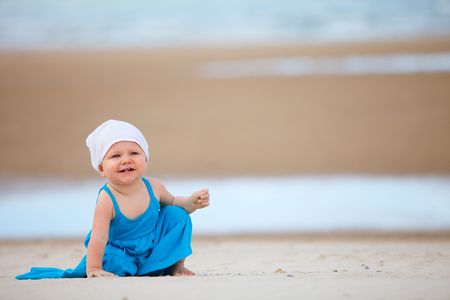 Cute baby girl in blue summer dress on the beachの写真素材