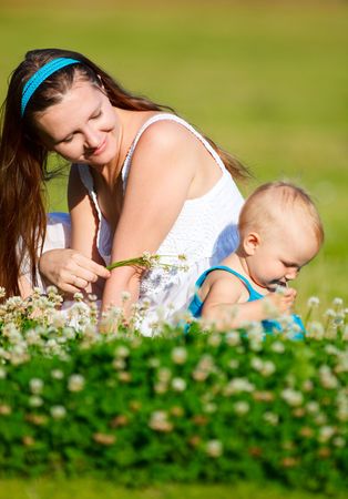 Mother and baby daughter having fun outdoors at sunny summer dayの写真素材