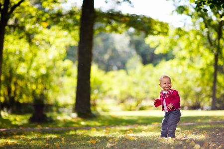 Cute 1 year old girl in beautiful park in autumn dayの写真素材