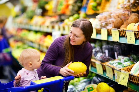 Young mother with baby daughter shopping in supermarketの写真素材