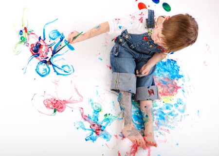 Cute 5 years old boy painting on white backgroundの写真素材