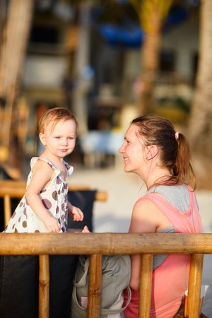 Young beautiful woman and her cute little daughter at beach caféの写真素材