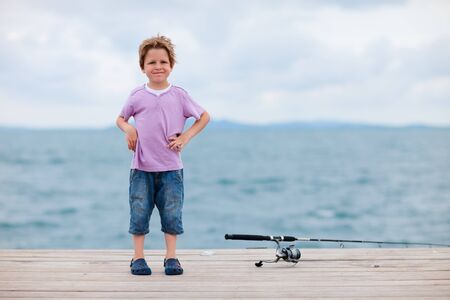 Cute 5 years old boy fishing from the jettyの写真素材