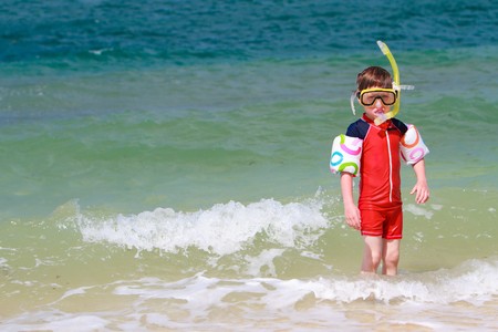 Cute 5 years old boy with snorkeling equipment on tropical beachの写真素材