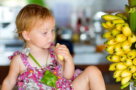 Outdoor portrait of cute toddler girl eating bananasの写真素材