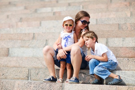 Young mother and two kids sitting on steps on summer dayの写真素材