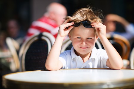 Cute little boy sitting in outdoor restaurant on summer dayの写真素材