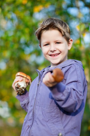 Portrait of cute happy boy with wild mushroomsの写真素材
