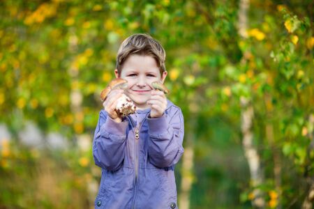 Portrait of happy kid showing two wild mushroomsの写真素材