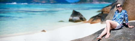 Panoramic photo of young beautiful woman relaxing on beach in Seychellesの写真素材
