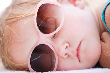 Portrait of adorable toddler girl sleeping at beachの写真素材