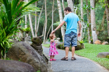 Father and his little daughter taking a walk at tropical parkの写真素材