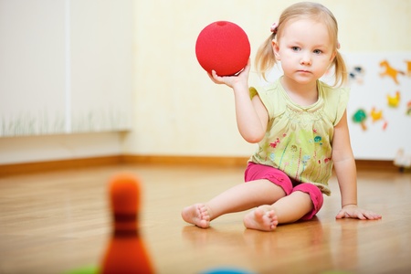 Adorable toddler girl playing bowling at homeの写真素材