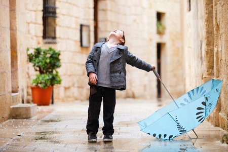 Cute little boy with umbrella looking up to skyの写真素材