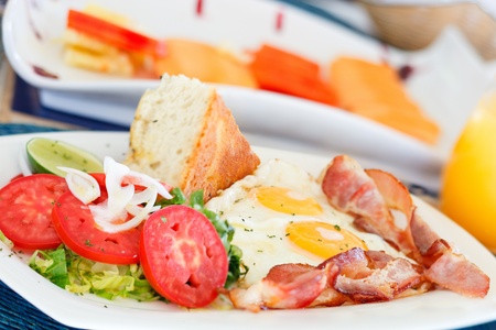 Delicious fried eggs with bacon and vegetables served for breakfastの写真素材