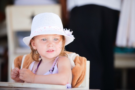 Casual portrait of adorable little girl sitting at beach restaurantの写真素材