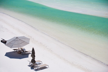 Above view of beach beds and umbrellas at tropical coast