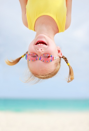 Adorable little girl hanging upside down having funの写真素材