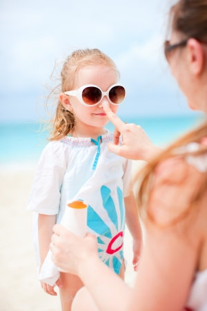 Mother applying sunblock cream on her daughters noseの写真素材