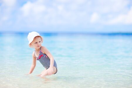 Adorable little girl in swimsuit at tropical beachの写真素材