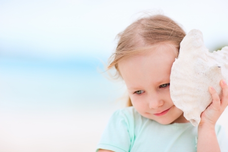 Adorable little girl with seashell at the beachの写真素材