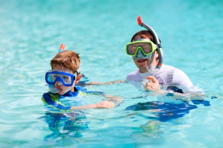 Father and son in ocean prepare for snorkelingの写真素材