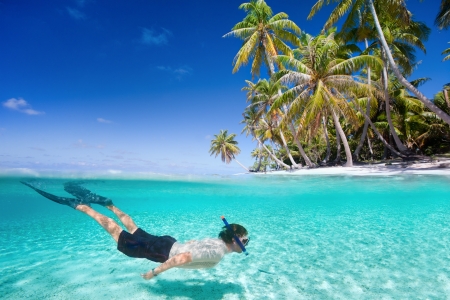 Man swimming in a clear tropical waters in front of exotic islandの写真素材