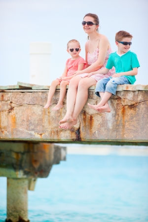 Mother and kids sitting on a wooden dockの写真素材