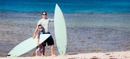 Father and son with surfboards at beach enjoying vacationの写真素材