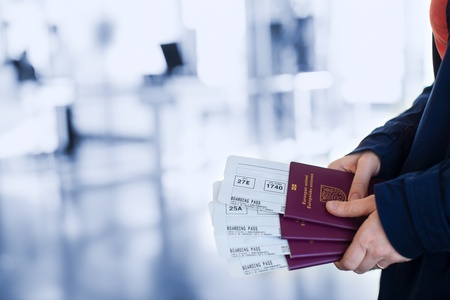 Close up of woman holding passports and boarding passport at airportの写真素材