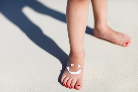 Close up of child feet with smile made with sun creamの写真素材