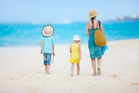 Back view of a mother walking with her two kids at tropical beachの写真素材