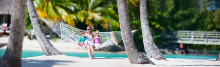 Mother and two kids relaxing on hammock at tropical beachの写真素材