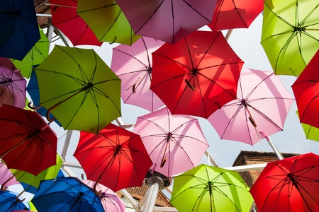 Street decorated with red, pink, green and blue umbrellasの写真素材