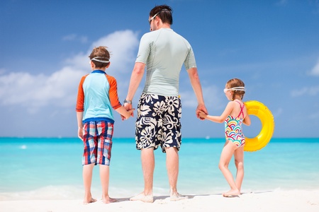 Back view of father and kids enjoying beach vacationの写真素材