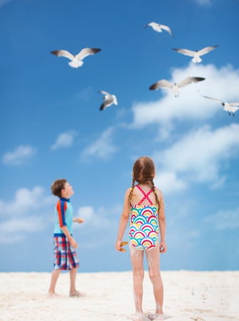 Two little kids and a flock of seagulls at beachの写真素材