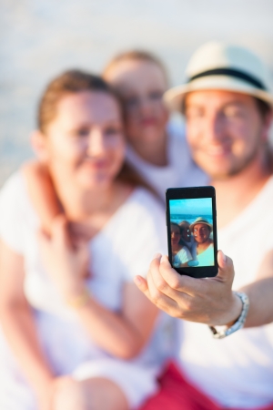 Beautiful family at beach making a self portrait with mobile phoneの写真素材