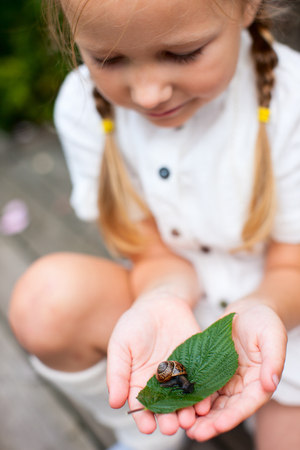 Little girl holding a snail in handsの写真素材